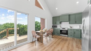 Een moderne keuken met groene kastjes, een houten eettafel en stoelen.