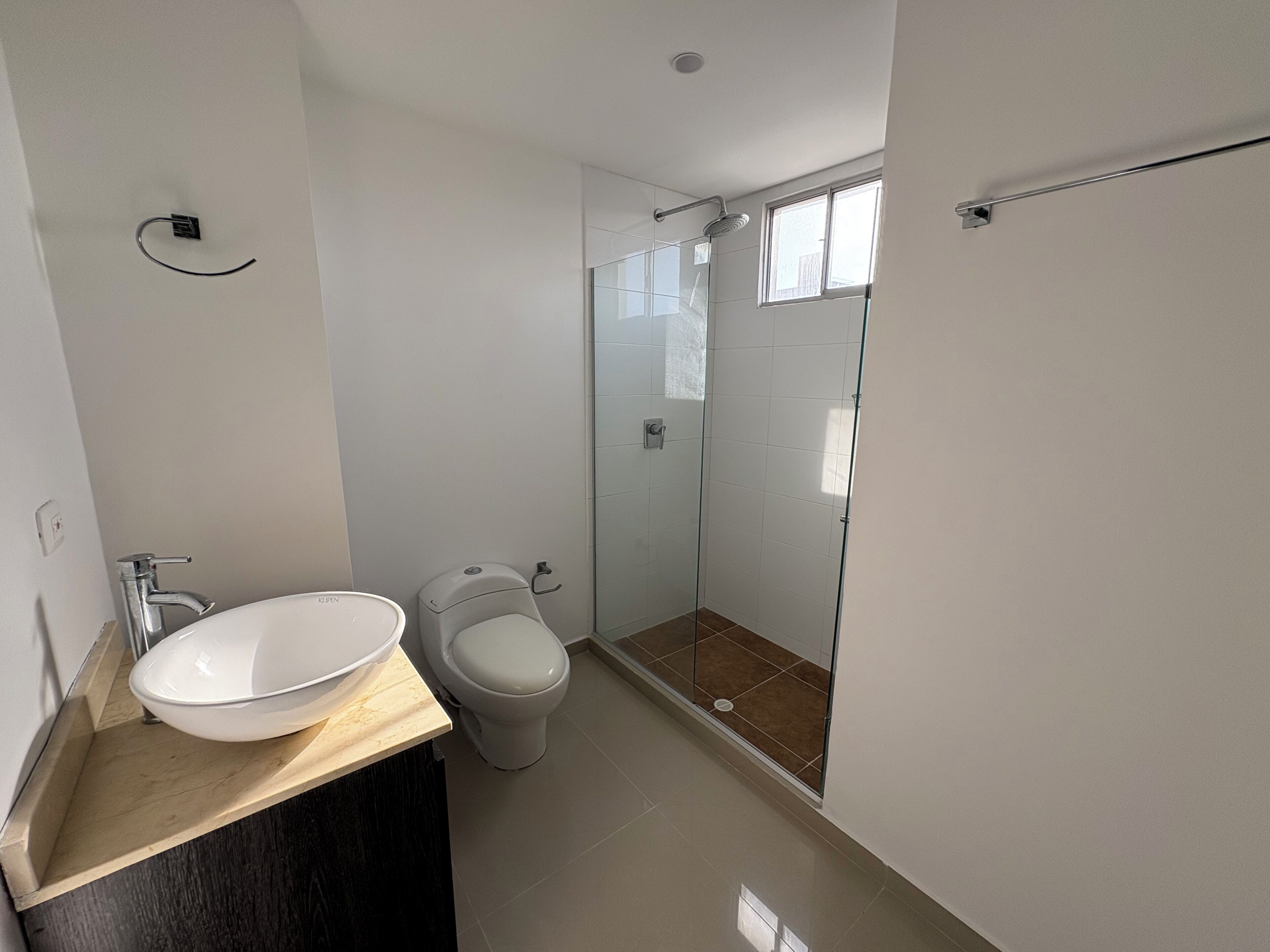 A modern bathroom with a white sink, toilet, and glass-enclosed shower.