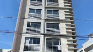 A multi-story building with balconies, a central entrance, and a sign reading "DELLINI."