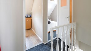 A narrow hallway with a wooden floor, white walls, and a white railing. - Holiday Home in Elim for Family (Elim)
