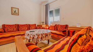 A room with a sofa set, a round table, and a picture on the wall. - A beautiful apartment for rent with everything you need. (Essaouira)