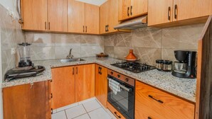 A kitchen with wooden cabinets, a gas stove, a coffee maker, and a blender. - A beautiful apartment for rent with everything you need. (Essaouira)