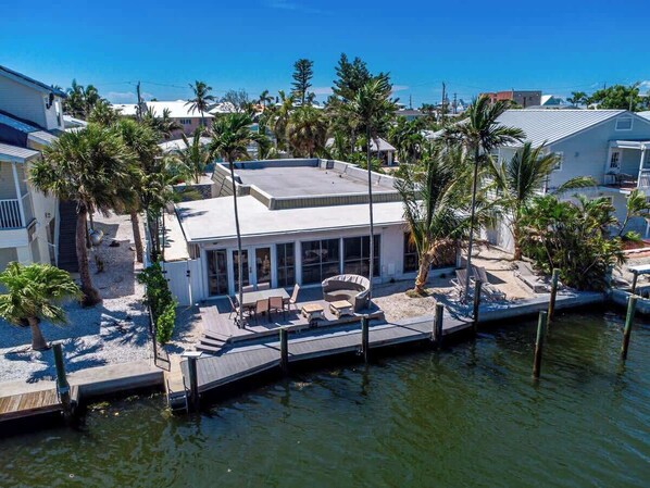 A waterfront property with a covered patio, outdoor furniture, and a dock extending into the water.