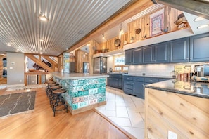 A modern kitchen with a bar area, wooden accents, and a unique patterned bar stool base.