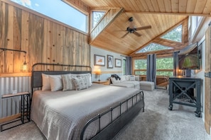 A bedroom with a bed, bedside tables, a desk, and a window.