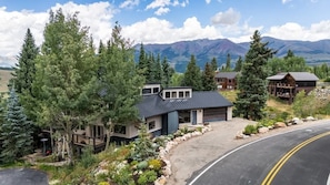 A mountain lodge with a modern design, a covered deck, and a view of the surrounding mountains.