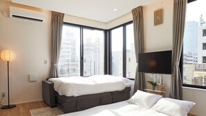 Un dormitorio moderno con una cama grande, una mesita de noche, una lámpara de pie y un televisor.