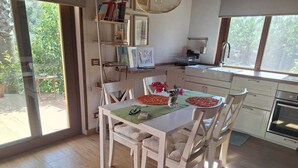 Een moderne keuken met een eetgedeelte, grote ramen en uitzicht op groen.