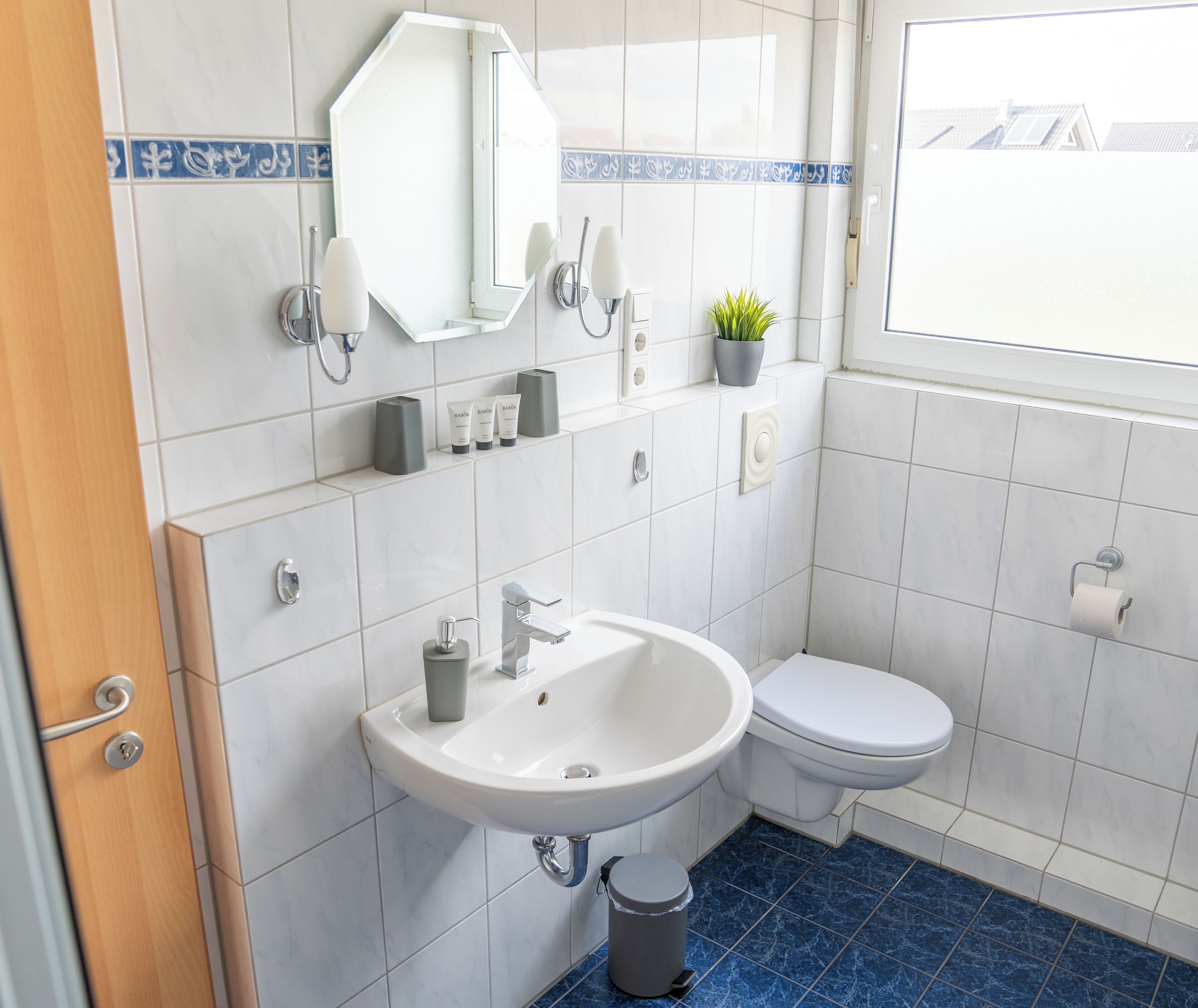 Un baño con lavamanos blanco, inodoro y espejo.