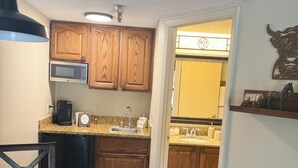 A compact kitchen with wooden cabinets, a microwave, a coffee maker, and a sink. - Ideal Condo in River Ranch • Across from the water park and near the rodeo (River Ranch)