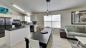 A modern kitchen with white cabinets, a central island, and pendant lighting. - Captain Bennett's Cove | 1mi to Beach + Community Pool (Panama City Beach)