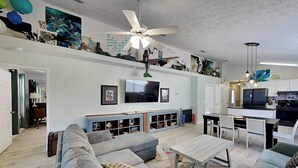 A living room with a sofa, coffee table, TV, and ceiling fan. - Captain Bennett's Cove | 1mi to Beach + Community Pool (Panama City Beach)