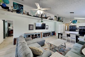 Ein Wohnzimmer mit Sofa, Couchtisch, Fernseher und Deckenventilator.