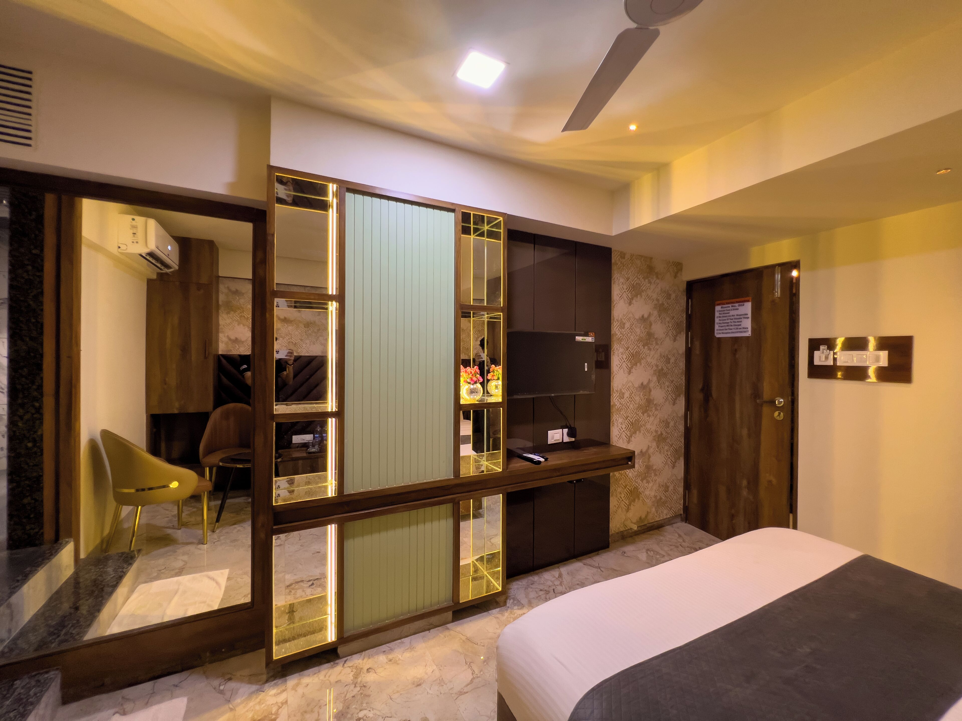A modern hotel room with a bed, a desk, a chair, and a wardrobe.