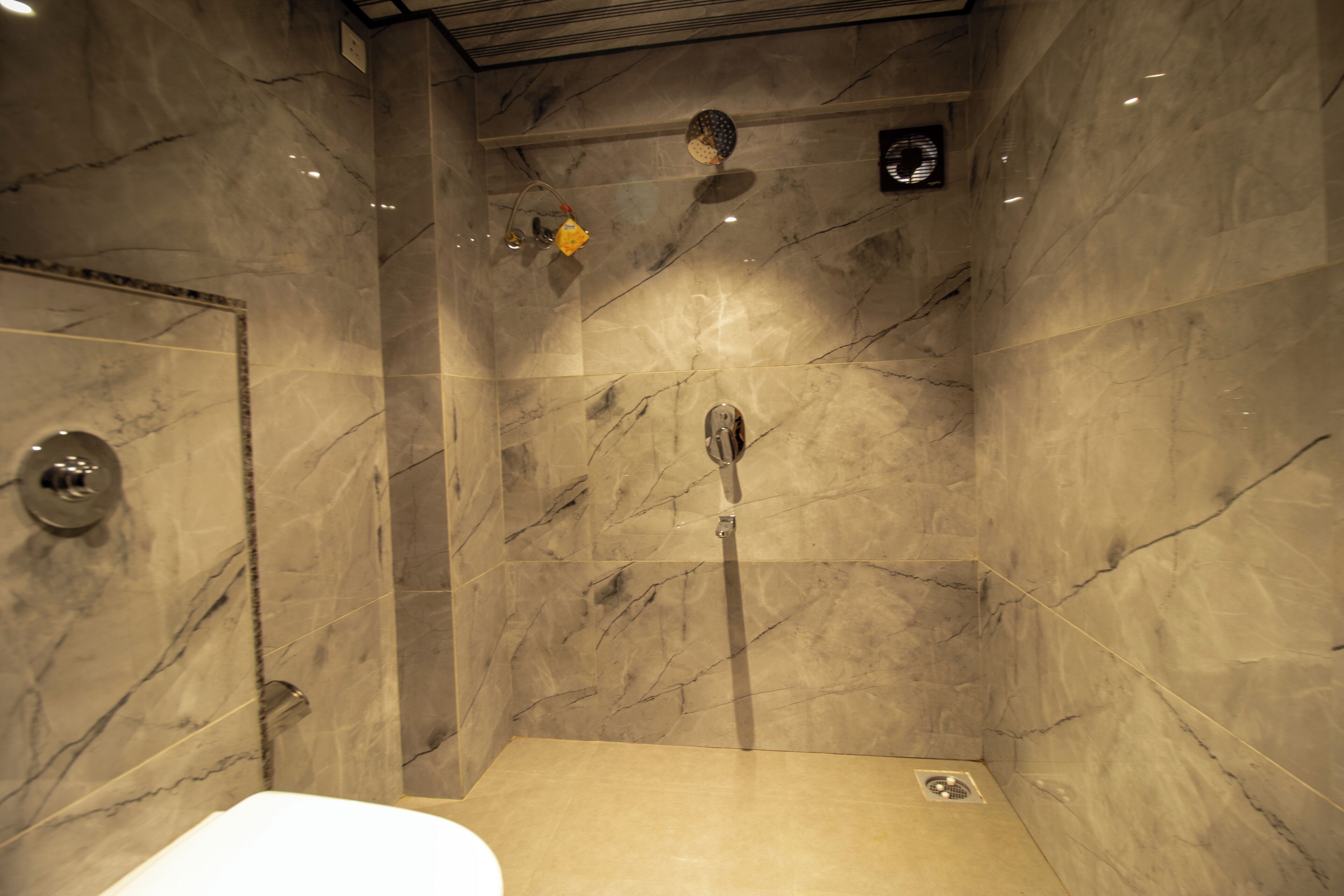 A bathroom with marble walls and a shower area.