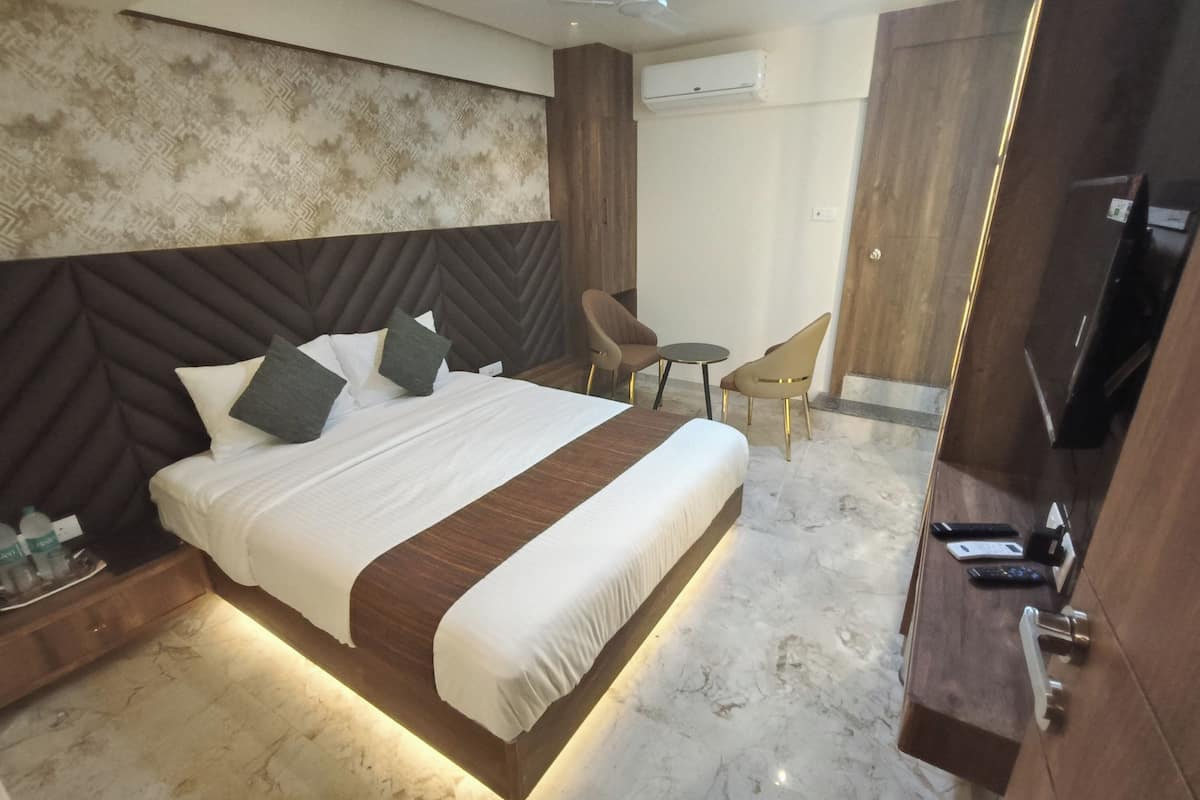 A modern hotel room with a large bed, a desk, a chair, and a television.