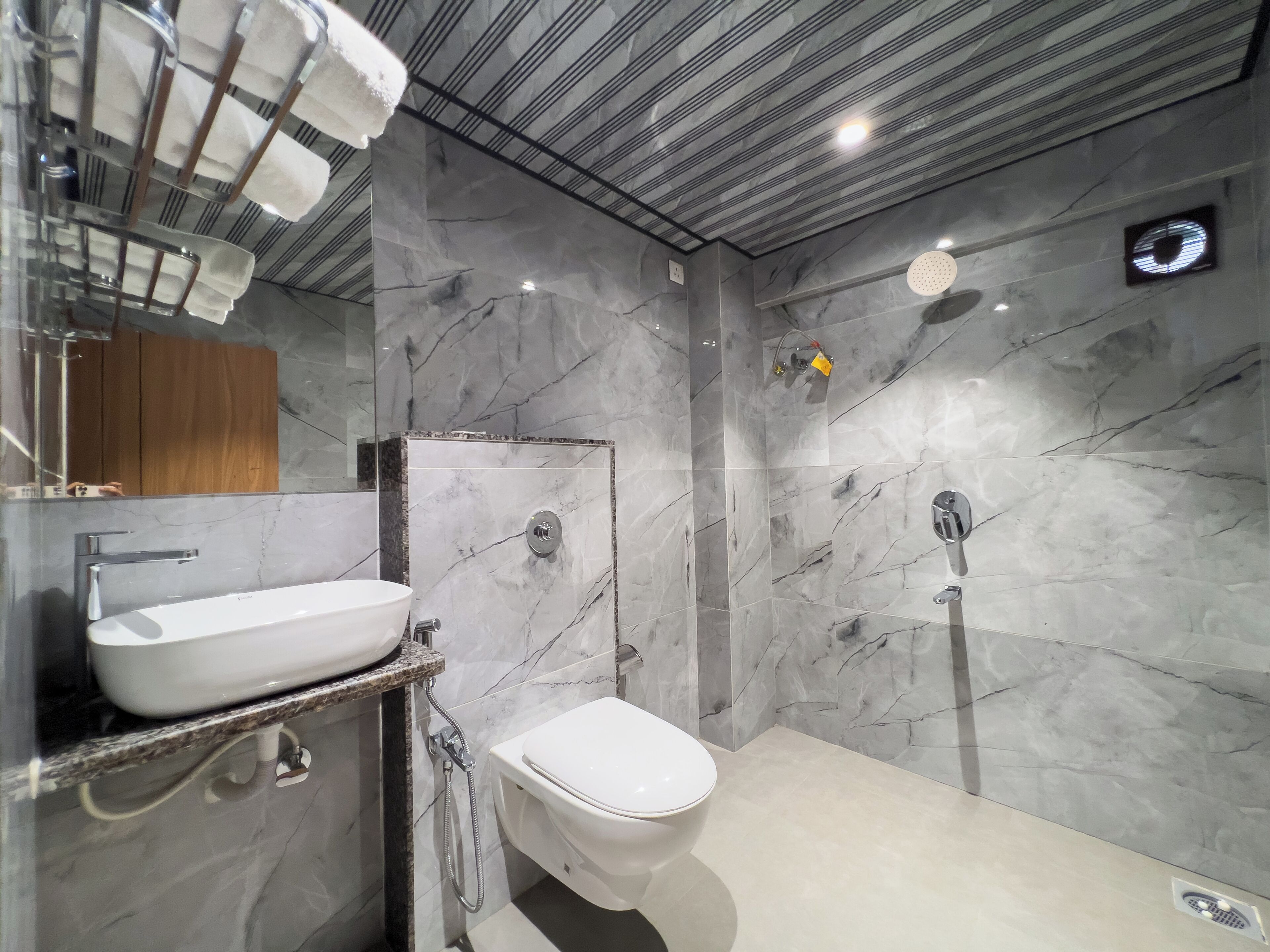Un baño moderno con pared de mármol, un lavabo blanco y un inodoro.