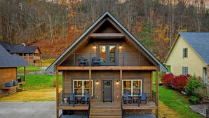 A two-story log cabin with a front porch, a balcony, and a deck. - New! 3BR w/Hot Tub*Arcade*5 Min to Pigeon Forge (Pigeon Forge)