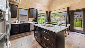 A modern kitchen with dark cabinetry, a granite countertop, and a large island. - New! 3BR w/Hot Tub*Arcade*5 Min to Pigeon Forge (Pigeon Forge)