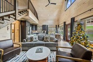 A spacious living area with a grey sofa, a coffee table, and a Christmas tree. - New! 5 Min to Pigeon Forge*Hot Tub*Fireplace*Games (Pigeon Forge)