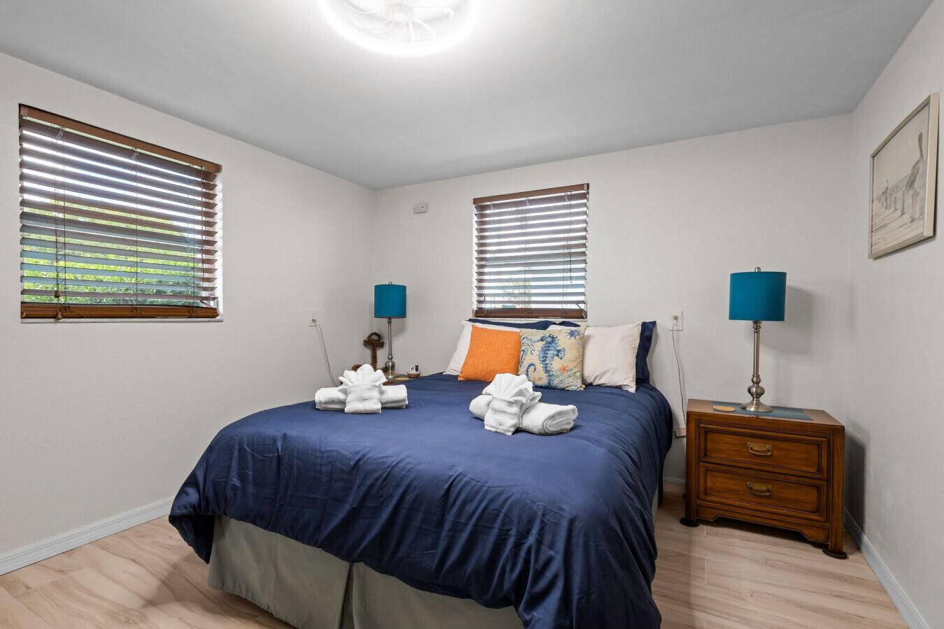 Une chambre à coucher comprenant un lit, deux tables de chevet, deux lampes et un luminaire au plafond.