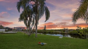 A grassy area with a hammock, a small pond, and palm trees. - Waterfront! 2BR w/Firepit & Grill! (Hudson)