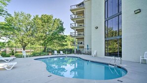 An outdoor swimming pool with lounge chairs and a building with balconies. - New! *Walk to Gatlinburg!* 2BR w/Balcony*Comm Pool (Gatlinburg)
