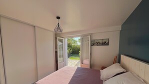 A bedroom with a bed, a door leading to a balcony, and a painting on the wall.