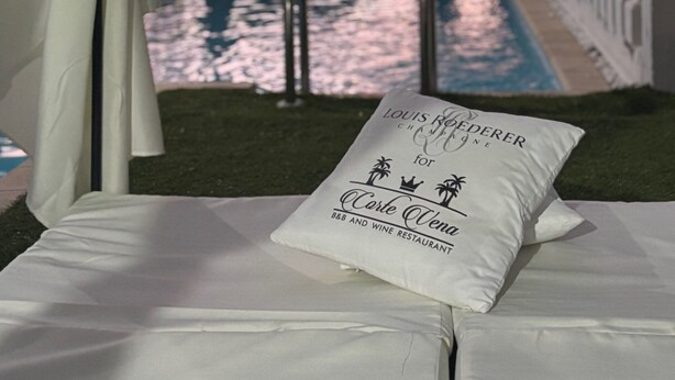 A poolside view with a canopy, a pillow with text, and a pool reflecting the sky. - Corte Vena Palace (Bianco)