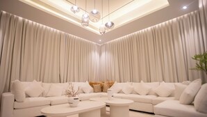 A modern living room with a sectional sofa, two round coffee tables, and a ceiling light fixture. - Luxury 5 Bedroom Villa Nad Al Sheba (Dubai)