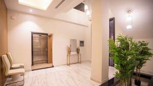 A modern lobby with a marble floor, a reception desk, a seating area, an elevator, and a large mirror. - Luxury 5 Bedroom Villa Nad Al Sheba (Dubai)