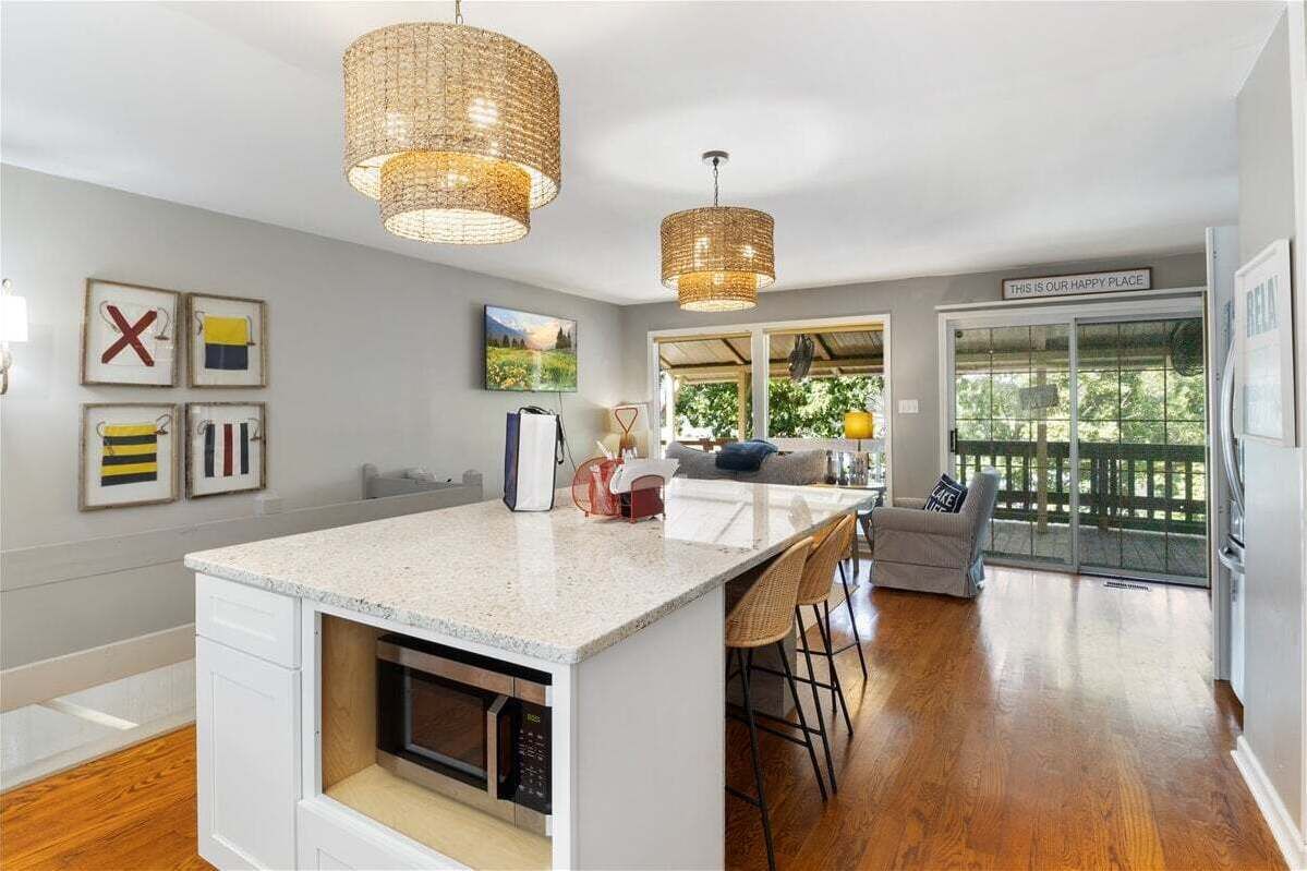 A modern kitchen with a large island, pendant lights, and a view to a deck.