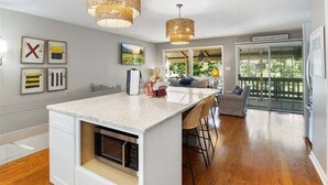 A modern kitchen with a large island, pendant lights, and a view to a deck. - Waterfront Home with Bunkhouse (Rocky Mount)