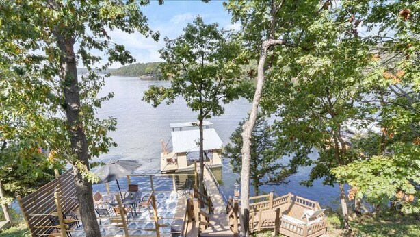 A wooden dock leading to a boat launch area with a view of a calm lake and distant hills. - Waterfront Home with Bunkhouse (Rocky Mount)