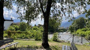 A park bench overlooking a river with a mountain in the background. - Residenza La Svolta - Salt Pool & Private Garden (Bellinzona)