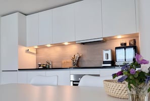 A modern kitchen with white cabinets, a black countertop, and a Bosch coffee machine.