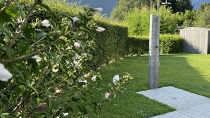 A garden with a pathway leading to a wooden structure, likely a sauna or hot tub, surrounded by lush greenery and a mountain backdrop. - Residenza La Svolta - Salt Pool & Private Garden (Bellinzona)