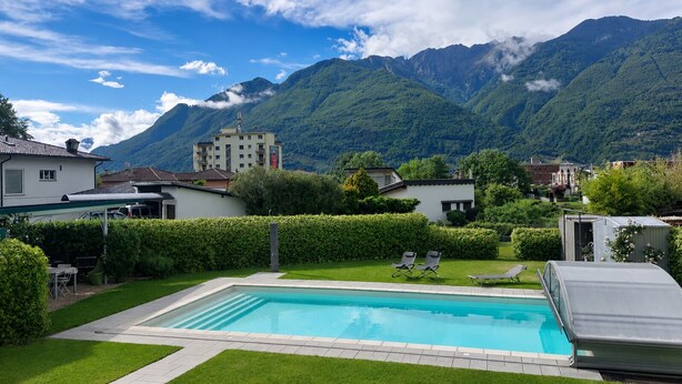 A swimming pool with lounge chairs, a small garden, and a mountain backdrop. - Residenza La Svolta - Salt Pool & Private Garden (Bellinzona)