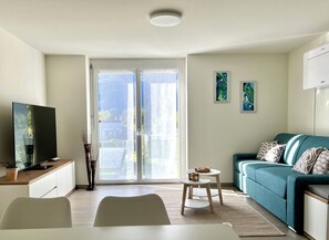 A modern living room with a television, a dining table, and a sofa.