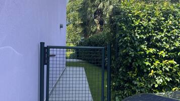 A gated entrance to a property with a paved pathway leading to a door.