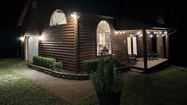 Una casa de madera con un porche cubierto, un garaje y un pequeño jardín.
