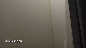 Een hoek van een kamer met dakraam, een witte muur en een zwart gordijn.