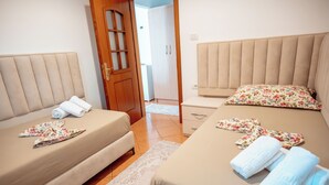 Une chambre d’hôtel avec deux lits, une armoire en bois et une petite table de chevet.
