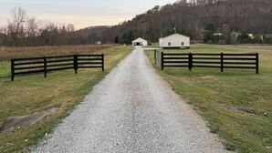 A gravel path leading to a white building with a black fence on either side.