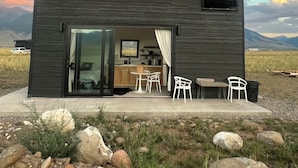 A modern cabin with a kitchen, dining area, and a large sliding glass door leading to a patio.