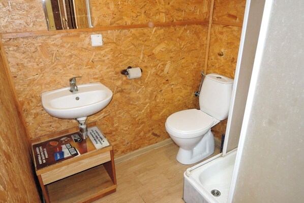 A small, compact bathroom with a wooden wall, a white sink, and a toilet. - Rustic Stay Surrounded by Forests (Kołczewo)