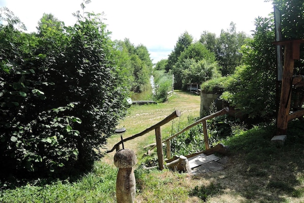 A rustic outdoor area with a wooden fence, a small wooden structure, and dense greenery.