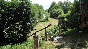A rustic outdoor area with a wooden fence, a small wooden structure, and dense greenery.