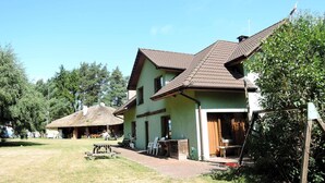 A two-story house with a tiled roof, a front porch, and a small outdoor seating area. - Nature & Fishing Retreat in Kołczewo (Kołczewo)