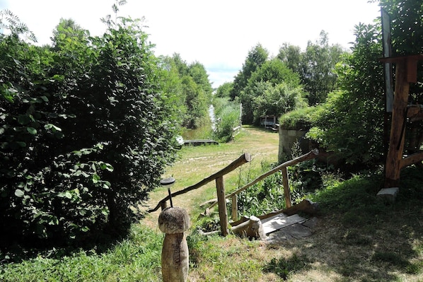 A rustic outdoor area with a wooden fence, a small wooden structure, and dense greenery. - Agritourism, relaxation in nature (Kołczewo)